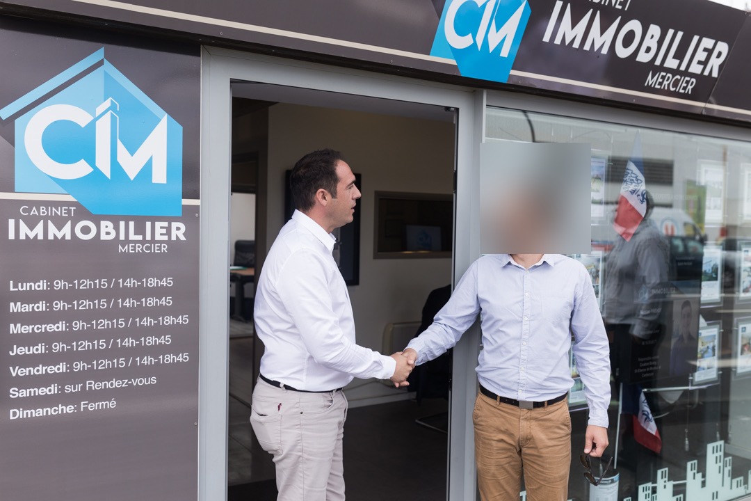 Échange devant le Cabinet Immobilier Mercier, visage du client anonymisé